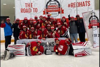A traditional group photo of a winning hockey team on the ice celebrating with a group photo. The team is in red jerseys.