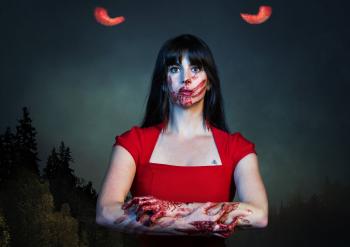 A women in a red dress looks towards the camera. Her face has a bloody hand print over her mouth. Her arms are folded in front of her and are covered in blood. Two red eyes peer at her through a dark sky behind her.