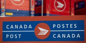 Photo of red mail boxes with the words Canada Post on them and the logo.