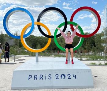 A woman poses with the Olympic rings at the Paris Olympics.