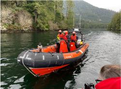 An orange rescue boat has three people on it durng training of the Coastal Nations Coast Guard Auxilary