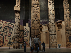 Totem poles fill the photo with a family looking up at them.