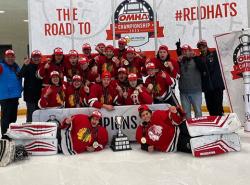 A traditional group photo of a winning hockey team on the ice celebrating with a group photo. The team is in red jerseys.