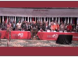 Chiefs of Ontario stand behind a man speaking at a podium.