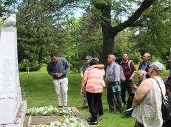 People gather around a stone monument in a cementary.
