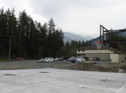 A mist gathers over far away mountains in the background. A cement pad has been marked out for a basketball court. A hoop and backboard are seen.